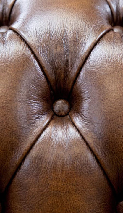 Macro close up of a single hand tied Chesterfield button and leather grain